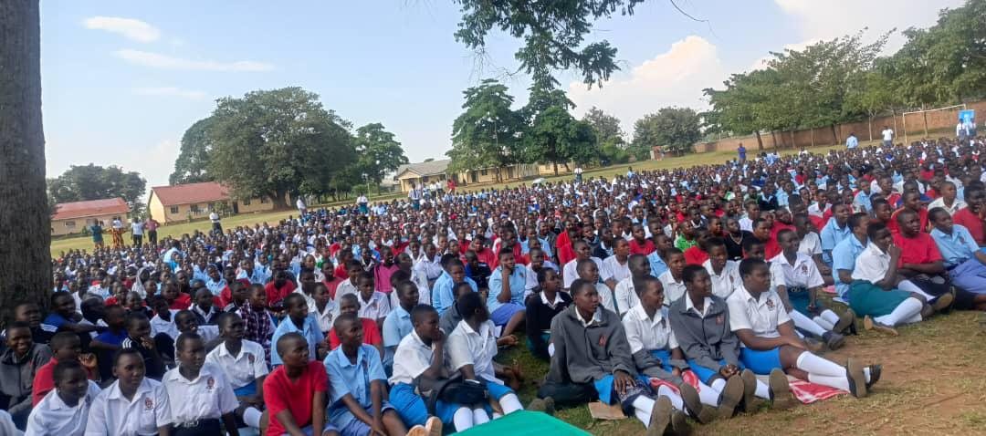 A large school assembly seated on the grounds